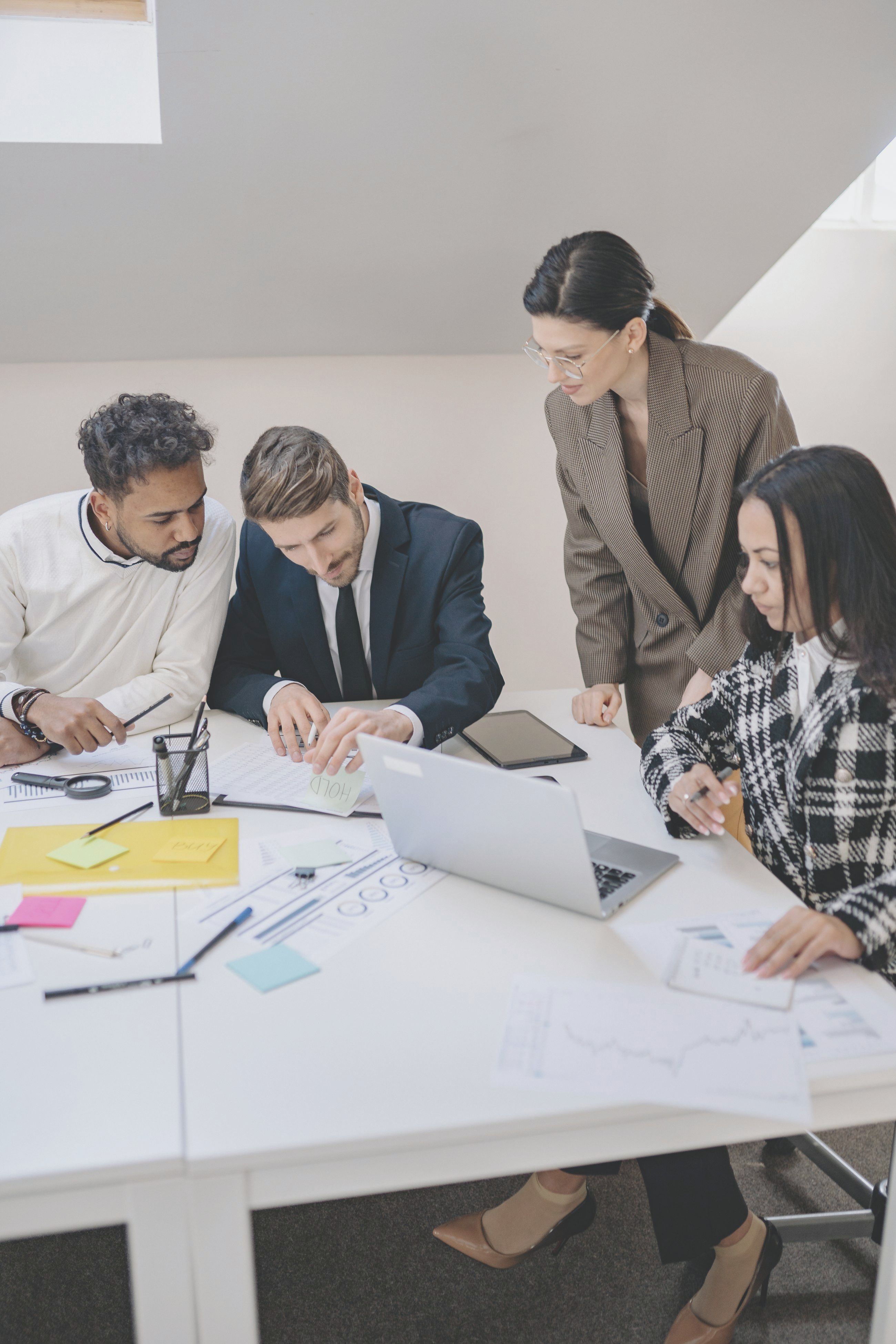 Four colleagues gathered around a table, reviewing plans together in soft daylight